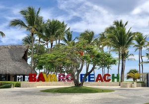 Picture of the beach with a Bavaro Beach sign and palm trees