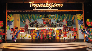 Stage with people in costumes dancing. The stage title reads "tropicalissimo".