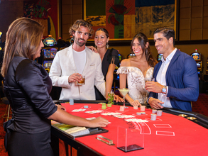 People drinking cocktails in a casino around a card game.